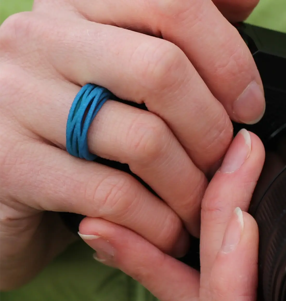 petrolgrüner Ring aus 3D gedrucktem Nylon aus der Serie Linie. Wie ein Faden wickelt sich eine Linie locker um den Finger